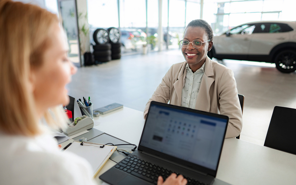 Car Salesperson Consulting Client At Modern Dealership Desk