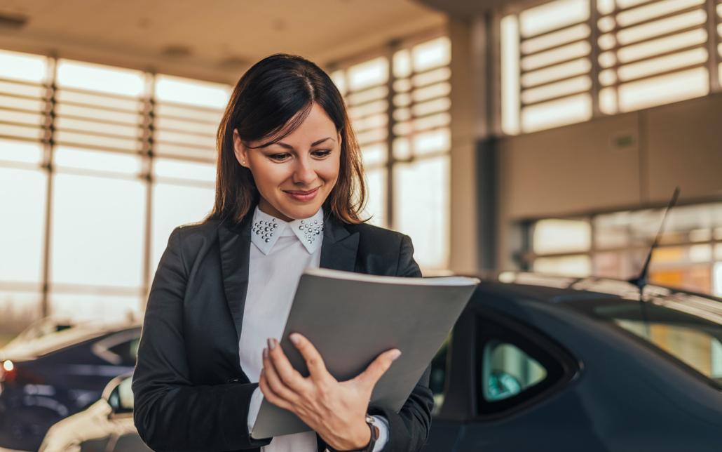 Woman Car Dealer In Showroom With Files