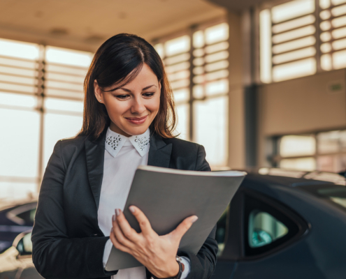 Woman Car Dealer In Showroom With Files